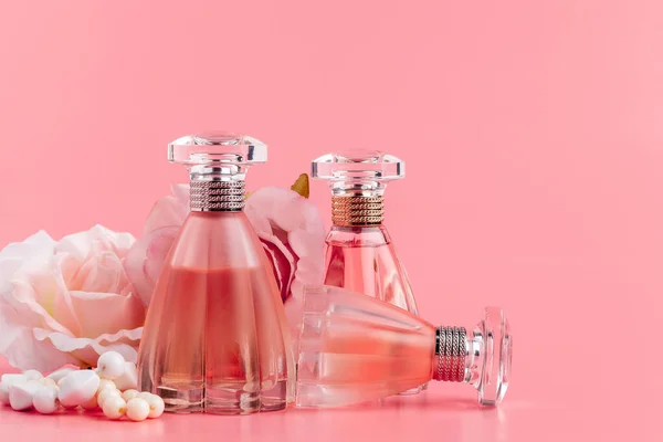 Parfümflasche mit Rosen auf rosa Stoff Hintergrund — Stockfoto