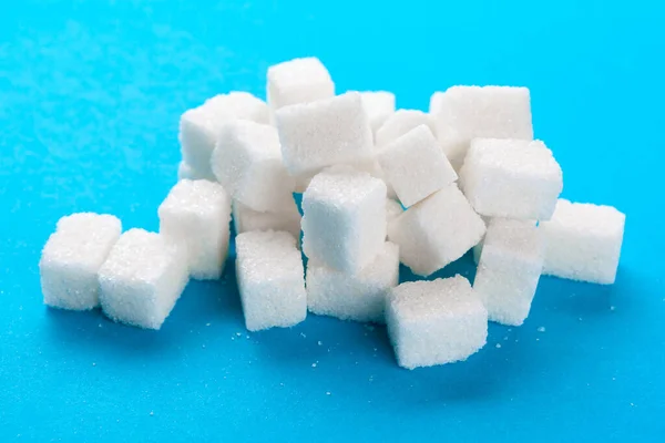 Cubos de açúcar branco em um fundo azul brilhante — Fotografia de Stock