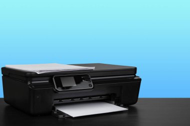 Siyah masada mavi arkaplana karşı sıkıştırılmış lazer yazıcı