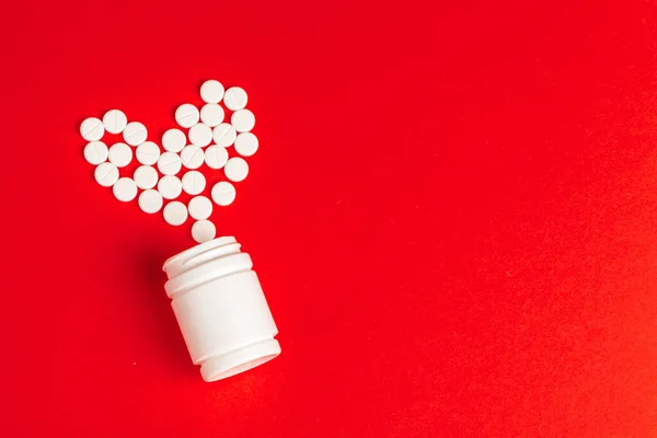 Tabletták szív ki tabletta palack piros háttér, felső nézet — Stock Fotó