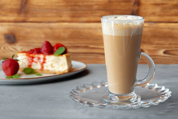 Glas latte kaffe och bit jordgubbscheesecake på grått bord — Stockfoto
