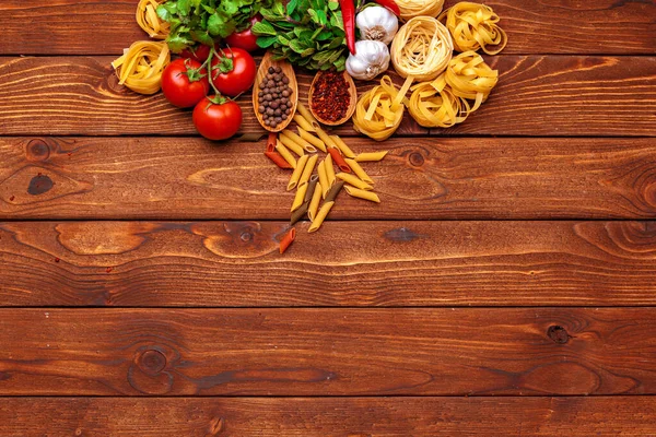 Pasta en ingrediënten op houten achtergrond met kopieerruimte. Bovenaanzicht. — Stockfoto