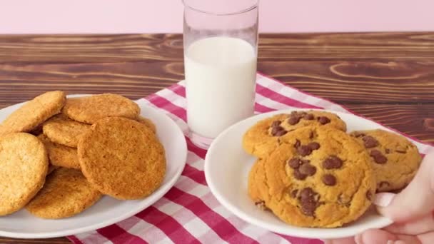 白盘上的巧克力曲奇饼和木制桌子上的牛奶杯 — 图库视频影像