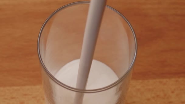 Yoghurt pouring into a glass and brim over the edgeon table, close up — Stock Video