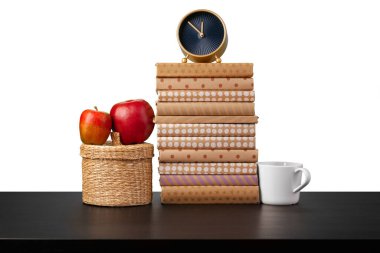 Alarm saati, beyaz arkaplan karşısında kitap yığını ve fincan