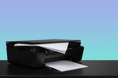 Siyah masada mavi arkaplana karşı sıkıştırılmış lazer yazıcı