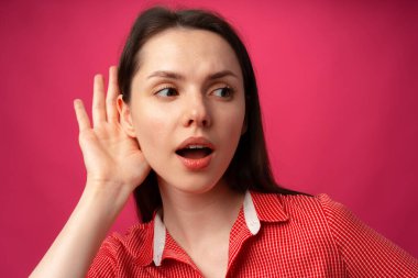 Genç kadınlar pembe arka planda duyduklarına şaşırırlar.