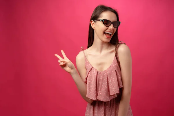 Jeune femme brune décontractée en lunettes de soleil sur fond rose — Photo