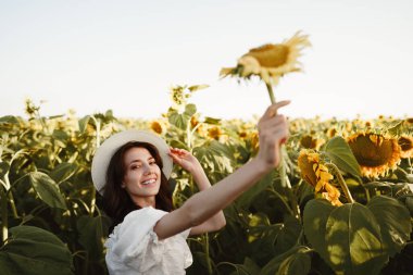Ayçiçeği tarlasında poz veren çekici genç kadın model.