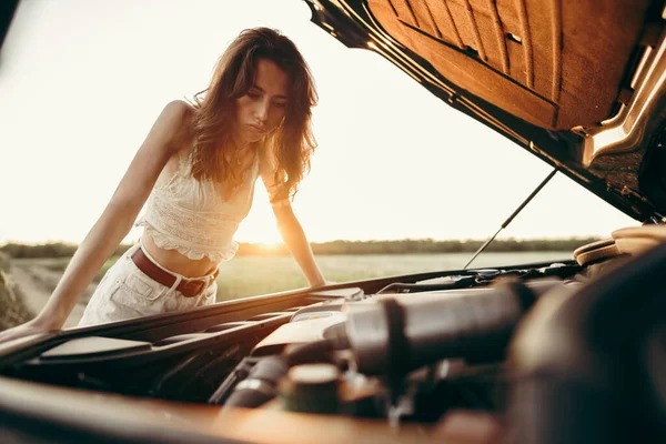 Jeune femme ouvrant le capot de sa voiture cassée dans la campagne — Photo