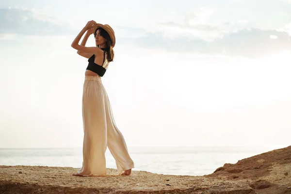 Jeune femme élégante debout sur la falaise à la mer au coucher du soleil — Photo