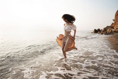 Yalnız genç kadın gün batımında sahilde yürüyor.