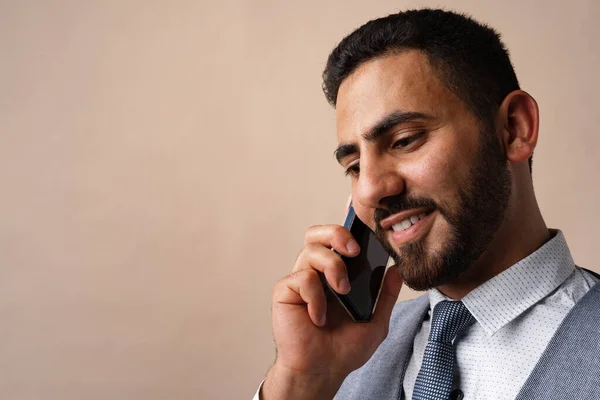 Арабський бізнесмен розмовляє по мобільному телефону проти бежевого походження — стокове фото
