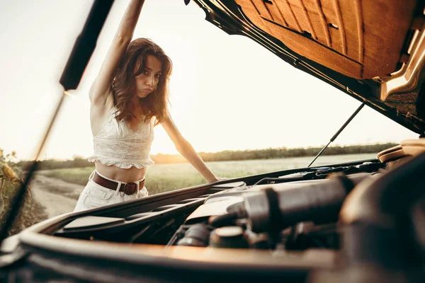 Junge Frau öffnet Motorhaube ihres kaputten Autos auf dem Land — Stockfoto