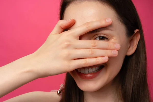 Junge Frau lächelt und bedeckt ihr Gesicht mit der Hand, Studioporträt — Stockfoto