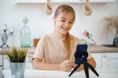 Küçük beyaz kız cep telefonuyla video görüşmesi yapıyor.