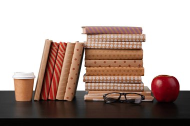 Masaüstünde beyaz arkaplana karşı kitap ve elma yığını