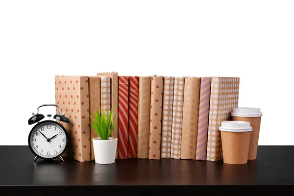 Relógio despertador, pilha de livros e xícara na mesa contra fundo branco — Fotografia de Stock