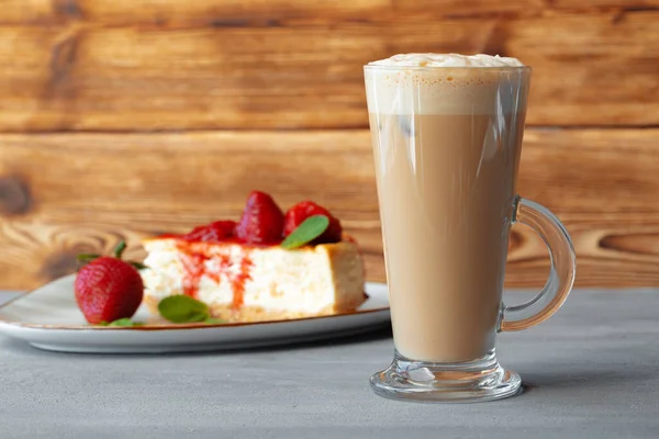 Glas latte kaffe och bit jordgubbscheesecake på grått bord — Stockfoto