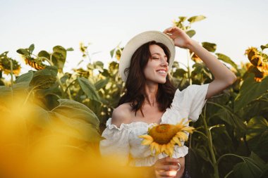 Ayçiçeği tarlasında poz veren çekici genç kadın model.