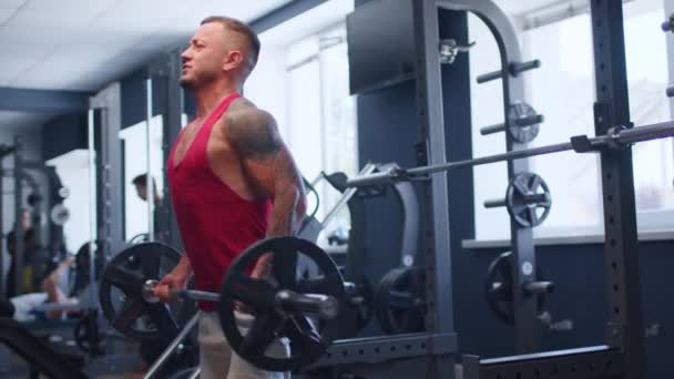 Atleta masculino haciendo ejercicio de rizo de barra en un gimnasio — Vídeo de stock