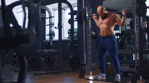 Joven fisicoculturista en forma haciendo sentadillas en el gimnasio — Vídeo de stock