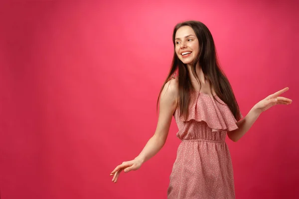 Joven mujer sonriente bailando con los brazos extendidos sobre fondo rosa — Foto de Stock