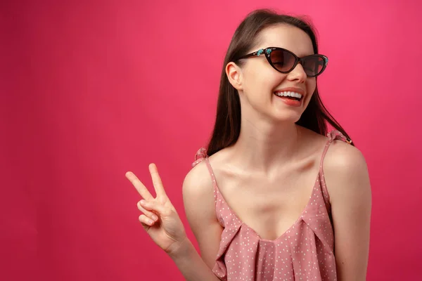 Jeune femme brune décontractée en lunettes de soleil sur fond rose — Photo