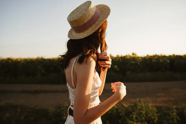 Молода жінка стоїть в полі на сході сонця насолоджуючись видом — стокове фото