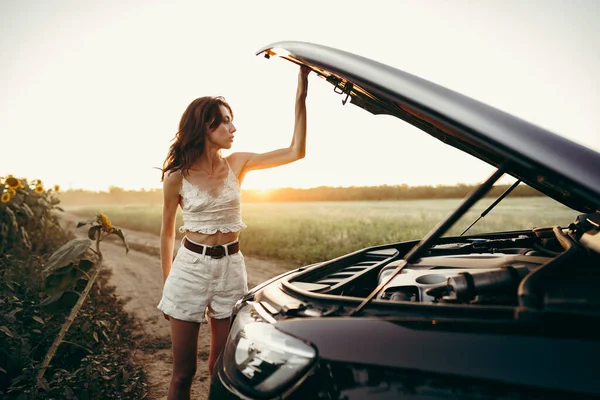 Junge Frau öffnet Motorhaube ihres kaputten Autos auf dem Land — Stockfoto