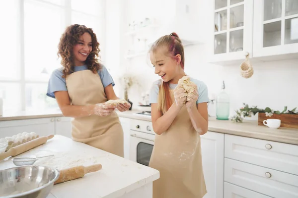 Menina adolescente ajudando sua mãe a cozinhar massa em sua cozinha em casa — Fotografia de Stock