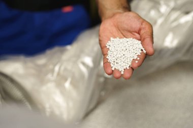 Plastik polimer granülleri tutan erkek elini kapat