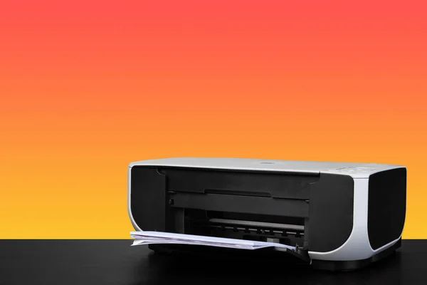 Compacte thuis laserprinter tegen oranje achtergrond — Stockfoto