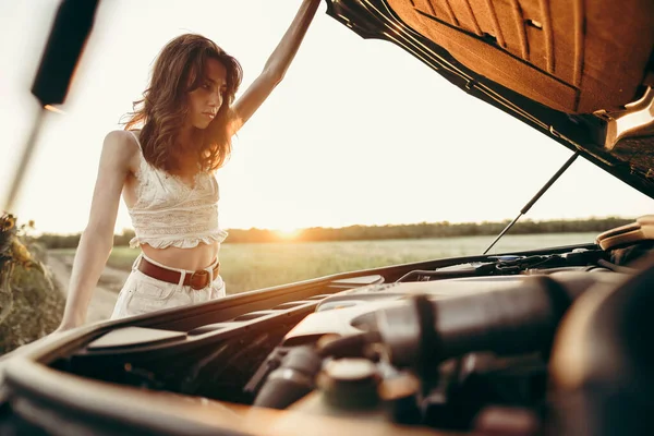 Junge Frau öffnet Motorhaube ihres kaputten Autos auf dem Land — Stockfoto