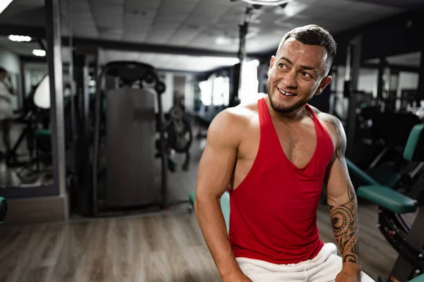 Portret van een man bodybuilder in rood shirt in de sportschool — Stockfoto