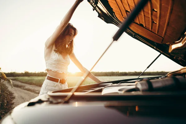 Junge Frau öffnet Motorhaube ihres kaputten Autos auf dem Land — Stockfoto