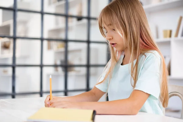 Teenagermädchen macht Notizen im Notizblock, zu Hause Hausaufgaben am Tisch — Stockfoto