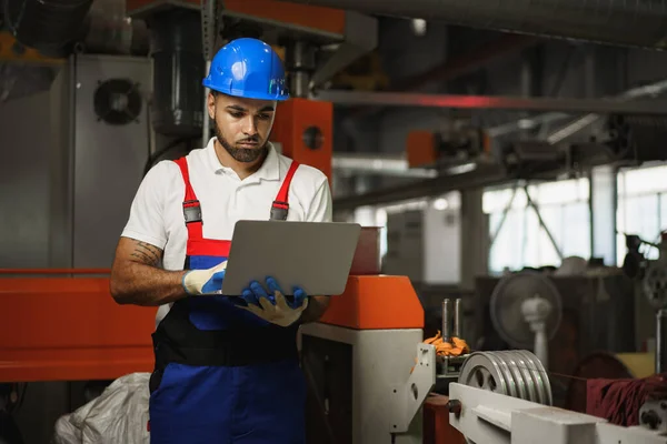 Industriarbetare med bärbar dator som arbetar i en anläggning för kabelproduktion — Stockfoto