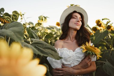 Ayçiçeği tarlasında poz veren çekici genç kadın model.