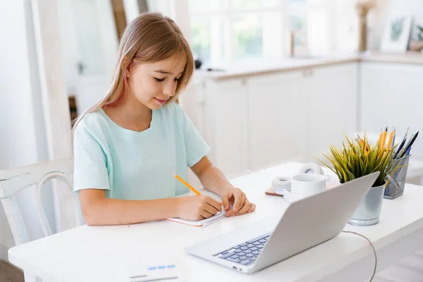 Adolescente haciendo notas en el bloc de notas, haciendo la tarea en la mesa en casa —  Fotos de Stock