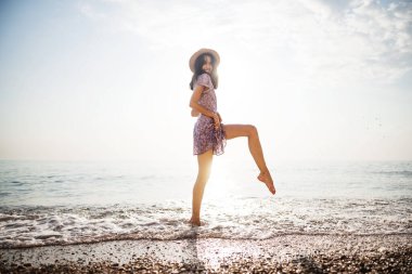 Gün doğumunda sahilde yürüyen genç bir kadının portresi.