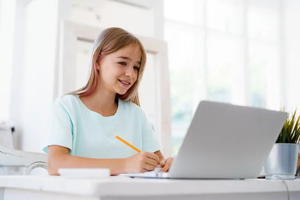 Chica joven usando el ordenador portátil para la tarea en casa —  Fotos de Stock