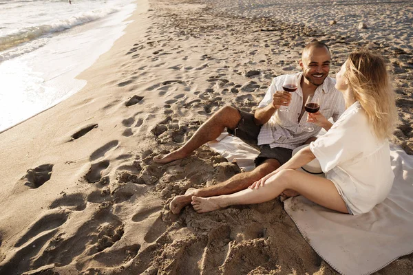 Retrato de um jovem casal sentado na praia e bebendo vinho — Fotografia de Stock