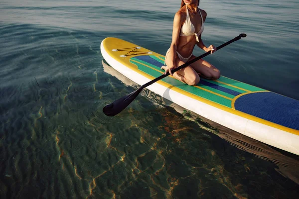 坐在立式划桨板上的年轻女子的近视 — 图库照片