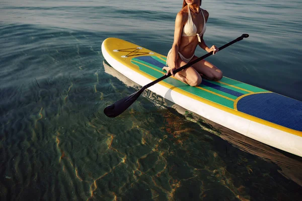 Nahaufnahme einer jungen Frau, die auf einem Stand Up Paddle Board sitzt — Stockfoto