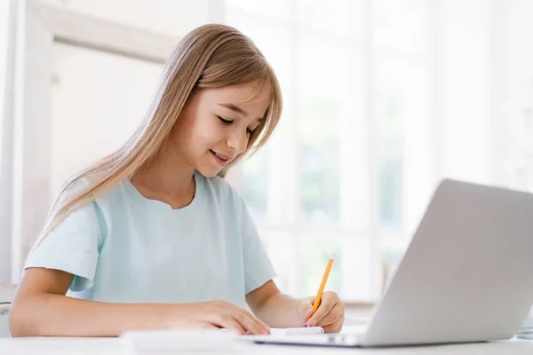 Chica joven usando el ordenador portátil para la tarea en casa —  Fotos de Stock