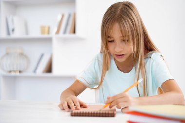 Genç kız not defterine not alıyor, evde ödev yapıyor.