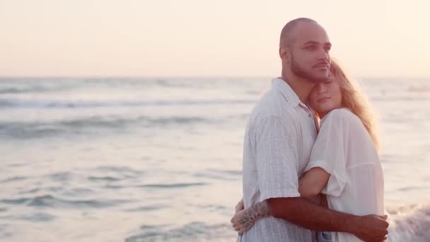 Jovem belo casal apaixonado de pé e abraçando na praia junto ao mar — Vídeo de Stock