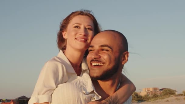 Joven hermosa pareja enamorada de pie y abrazándose en la playa junto al mar — Vídeos de Stock