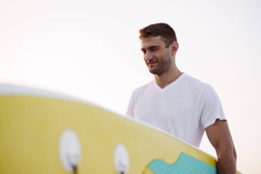 Su sörfü seansından sonra yiyecek taşıyan genç adam.